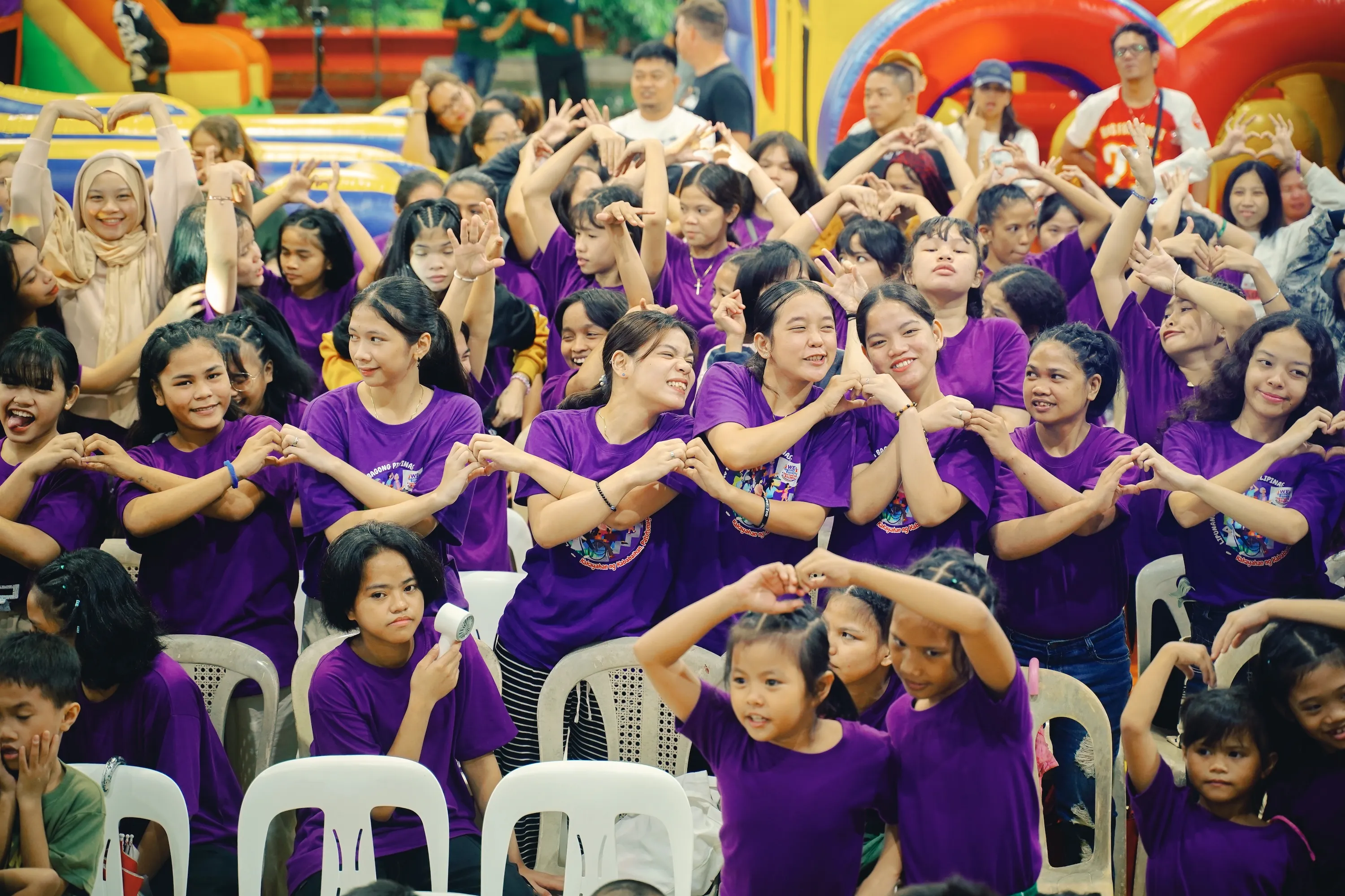 Young girls smiling and making hearts with their hands, wearing purple